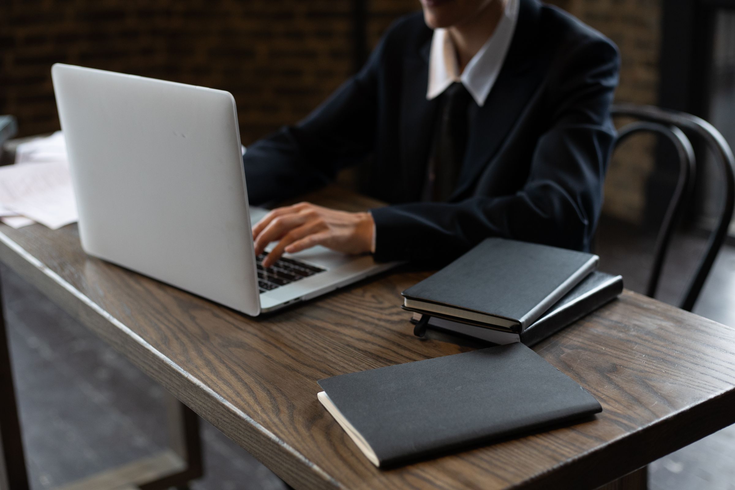 Professional working at a wooden desk with laptop and notebooks