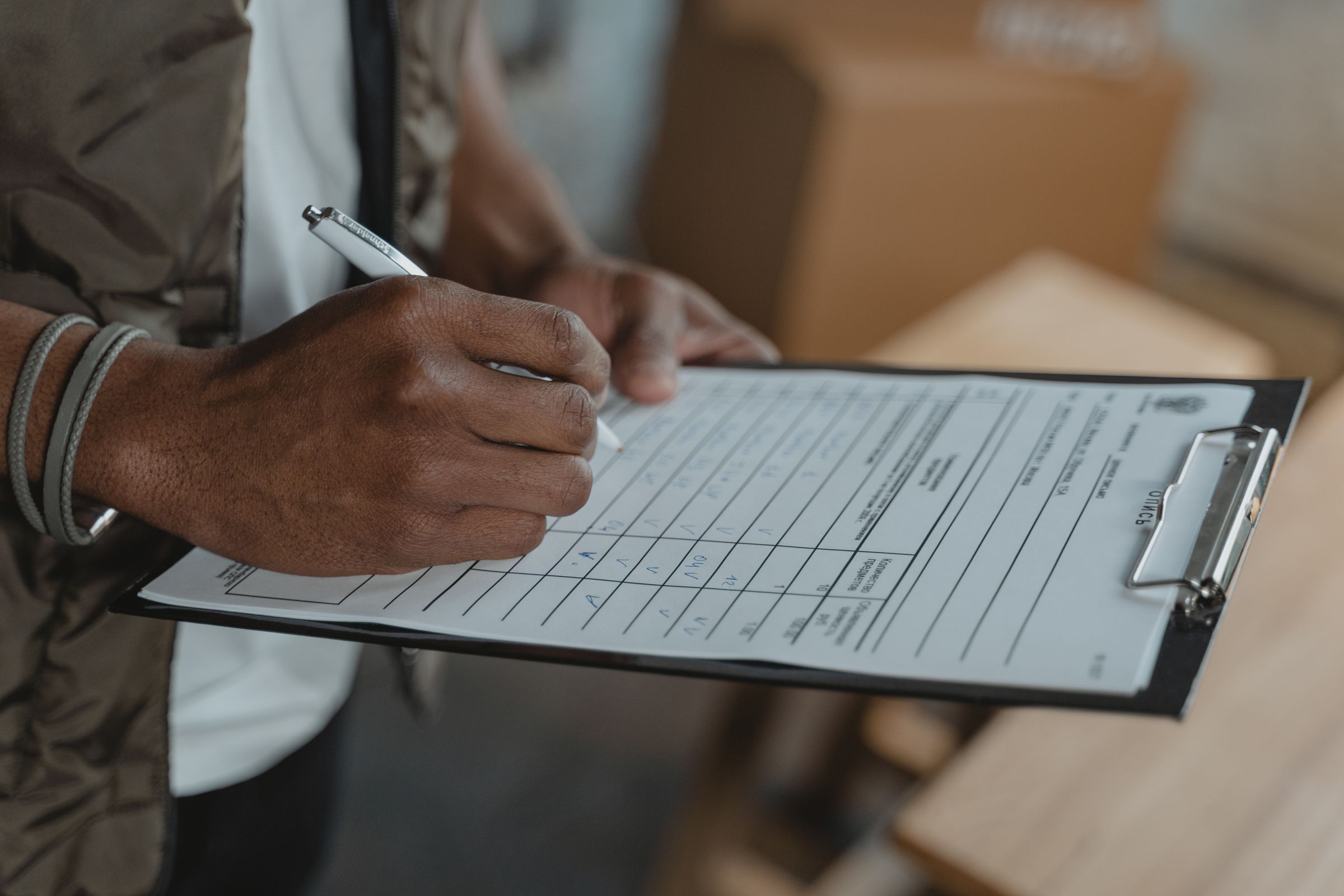 Hand completing a checklist form on a clipboard