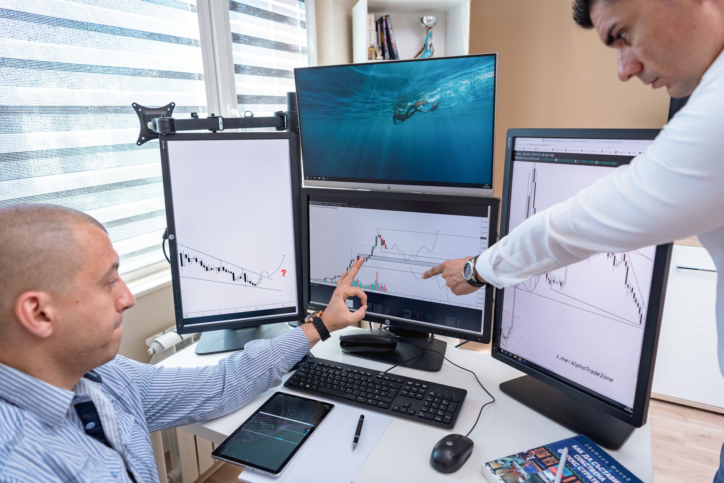 Two professionals monitoring data on multiple screens