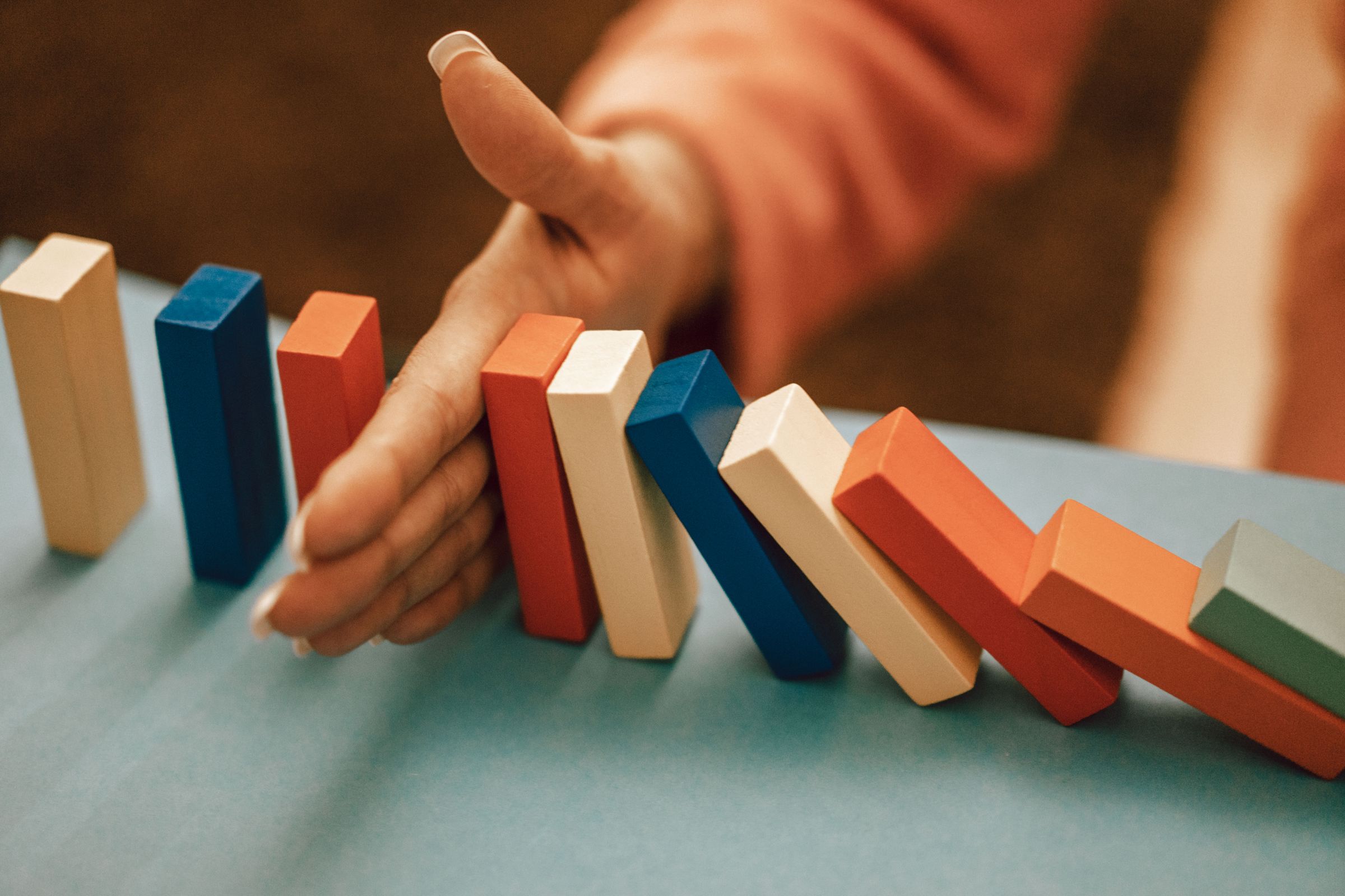 Hand stopping a row of falling dominoes